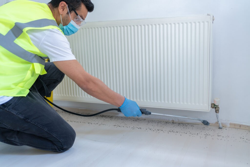 Person in safety gear inspecting radiator amid scattered debris.